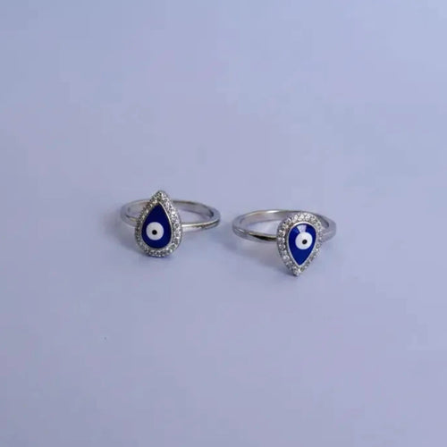 Silver toe rings with blue and white evil eye design on a solid background