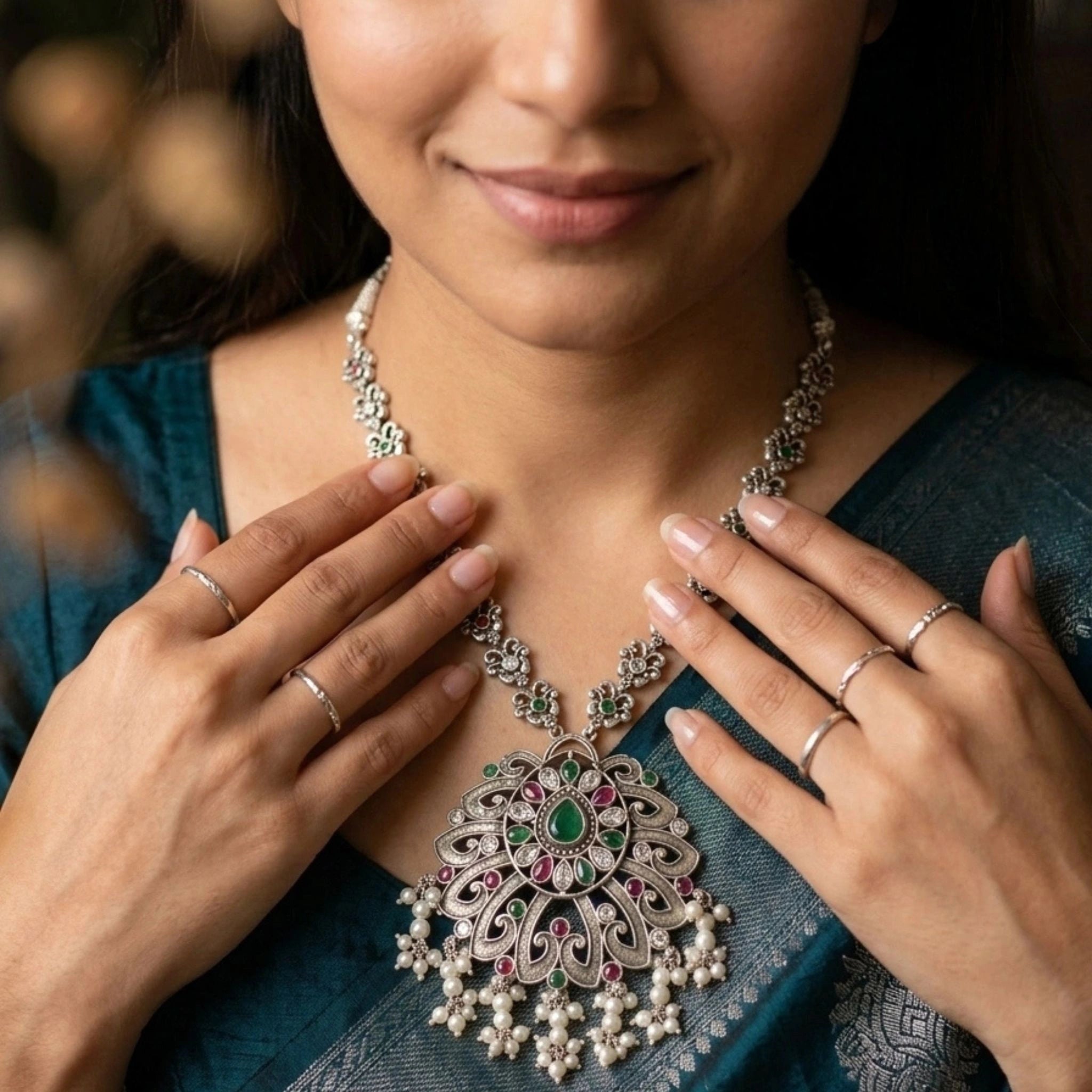 Woman wearing a decorative silver necklace with gemstones, close-up on face and necklace.