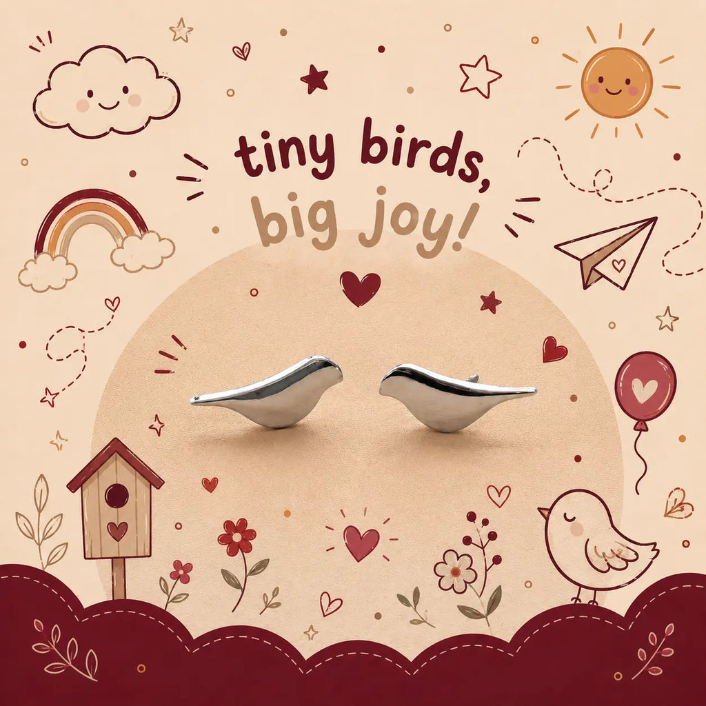 A pair of small silver bird-shaped earrings displayed on a beige background with a whimsical doodle-style illustration featuring a rainbow, sun, clouds, birdhouse, and the text 'tiny birds, big joy!'.