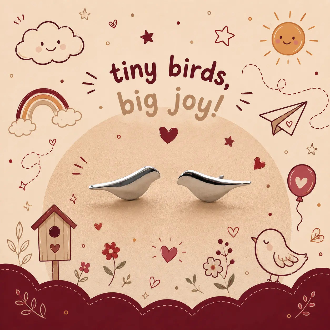 A pair of small silver bird-shaped earrings displayed on a beige background with a whimsical doodle-style illustration featuring a rainbow, sun, clouds, birdhouse, and the text 'tiny birds, big joy!'.