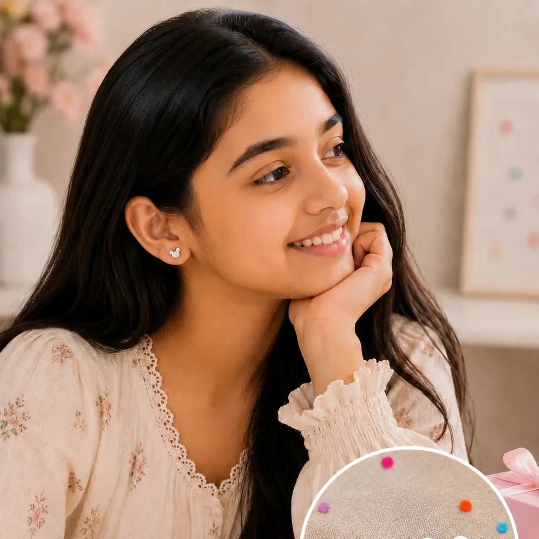A young girl with long dark hair smiles while wearing a small white stud earring. An inset circle at the bottom right shows the pair of white stud earrings on a textured surface with colorful dots.