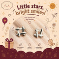 A pair of small silver stud earrings shaped like a ladder, displayed on a soft cream fabric background with decorative text and illustrations including 'Little stars, bright smiles!' and product callouts.
