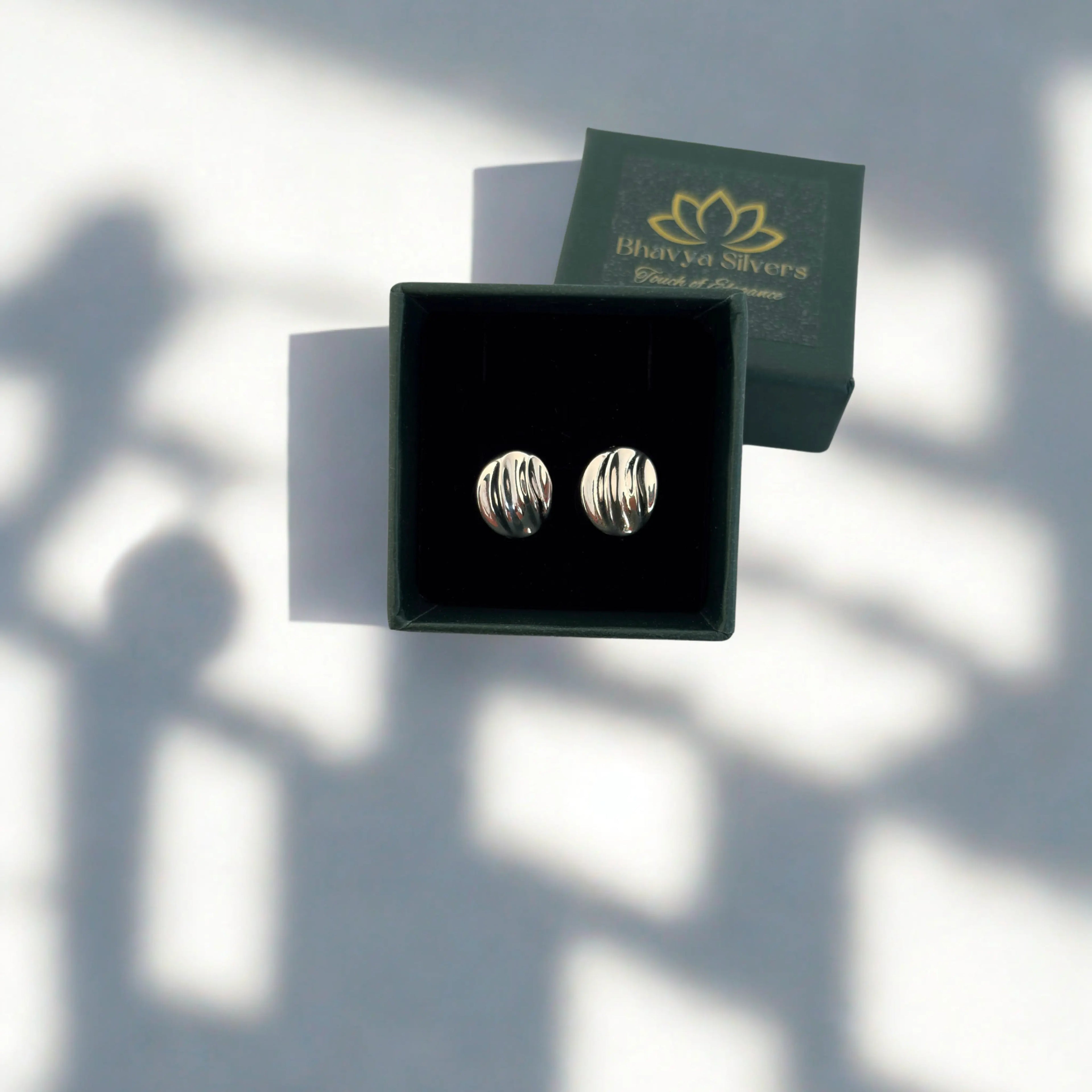 Silver earrings in a box with Bhavya Silvers packaging on a white background