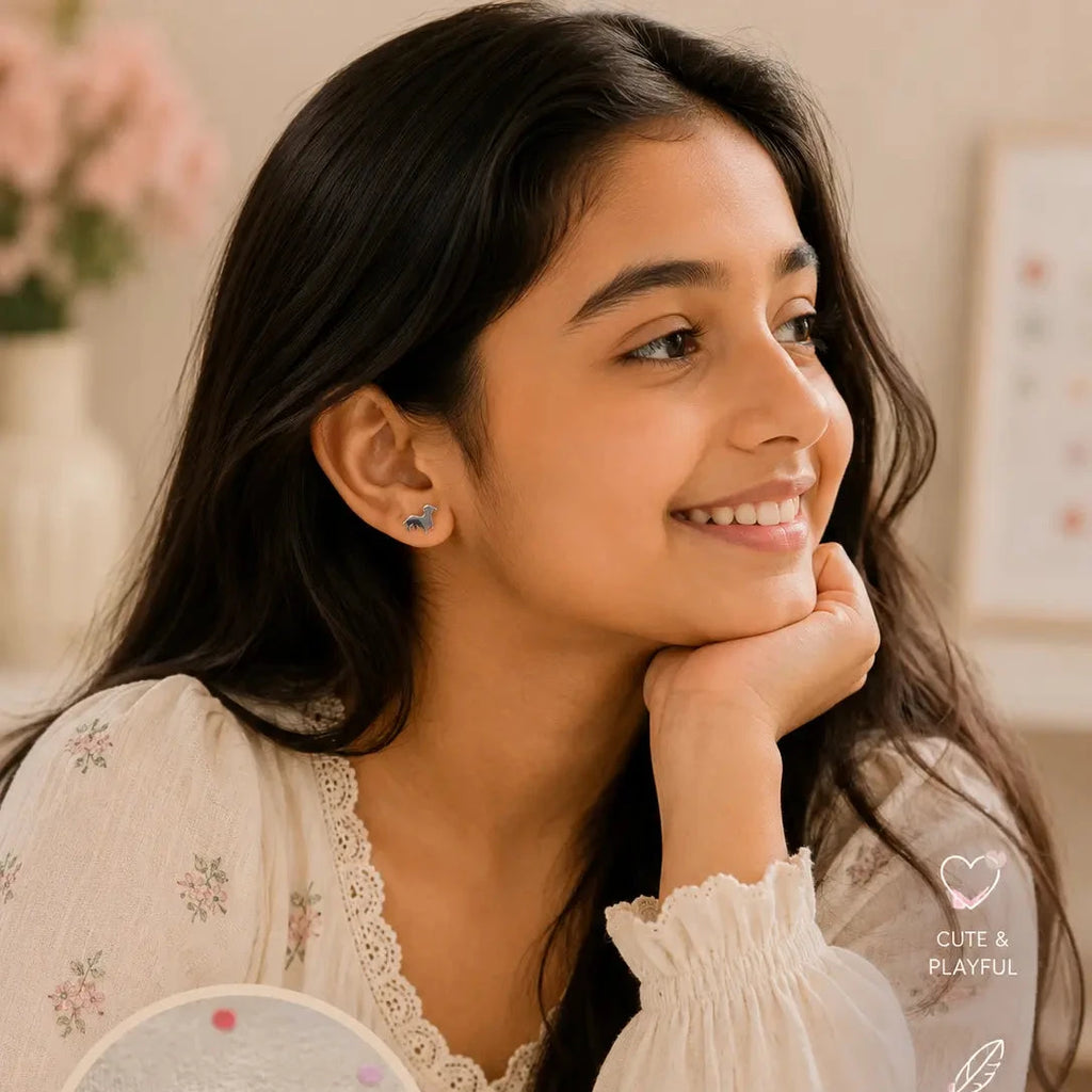 A young girl with long dark hair smiles while resting her chin on her hand, wearing a white floral top.
