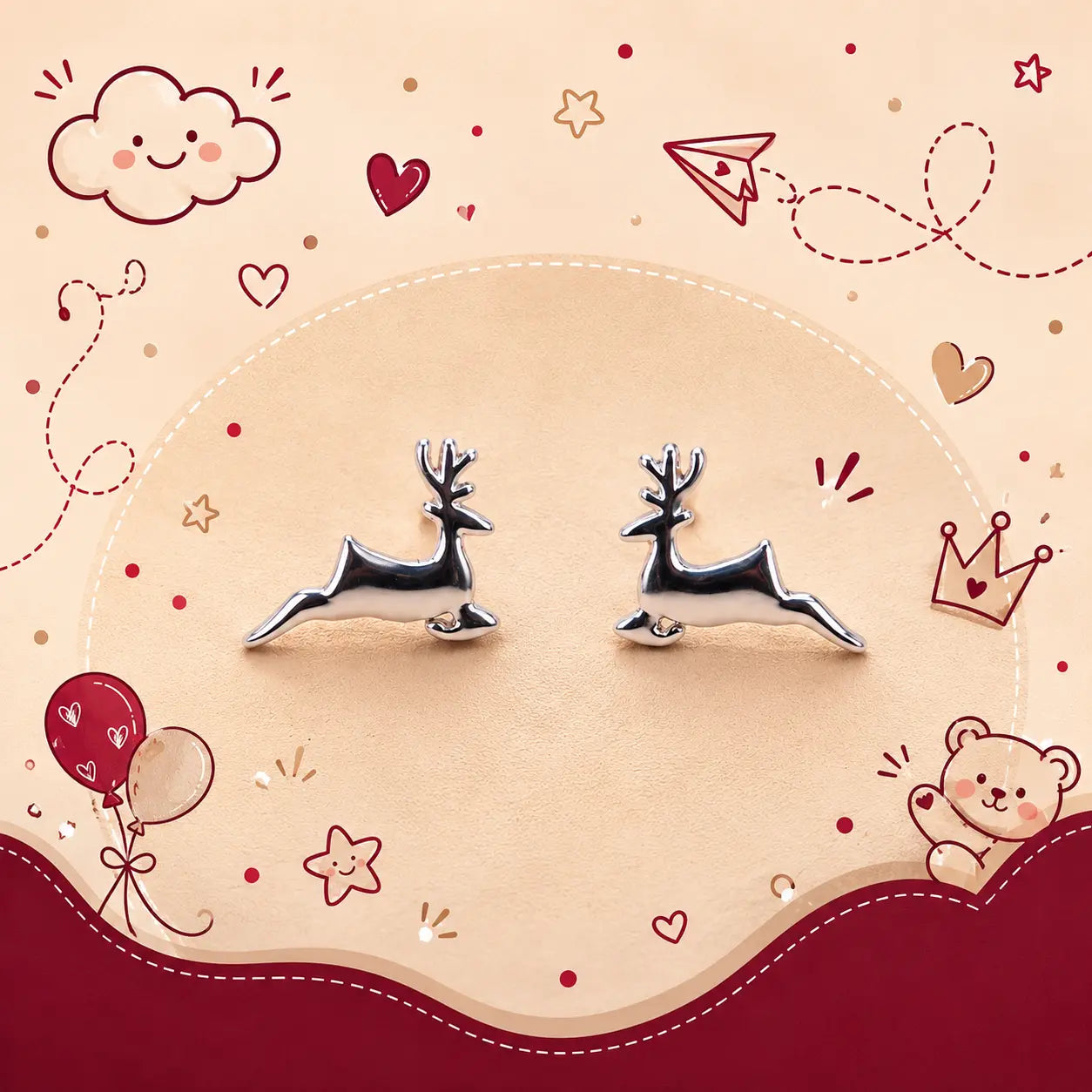 A pair of silver deer stud earrings displayed on a beige circular background with cute red and pink cartoon doodles including hearts, stars, balloons, a cloud, and a teddy bear.