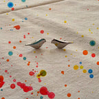 Bird shaped earrings on beige color linen fabric