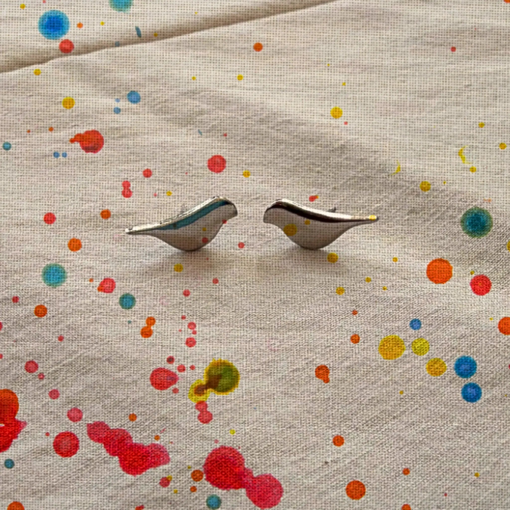 Bird shaped earrings on beige color linen fabric