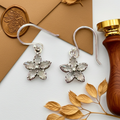Crystal floral earrings flatlay on white and brown background